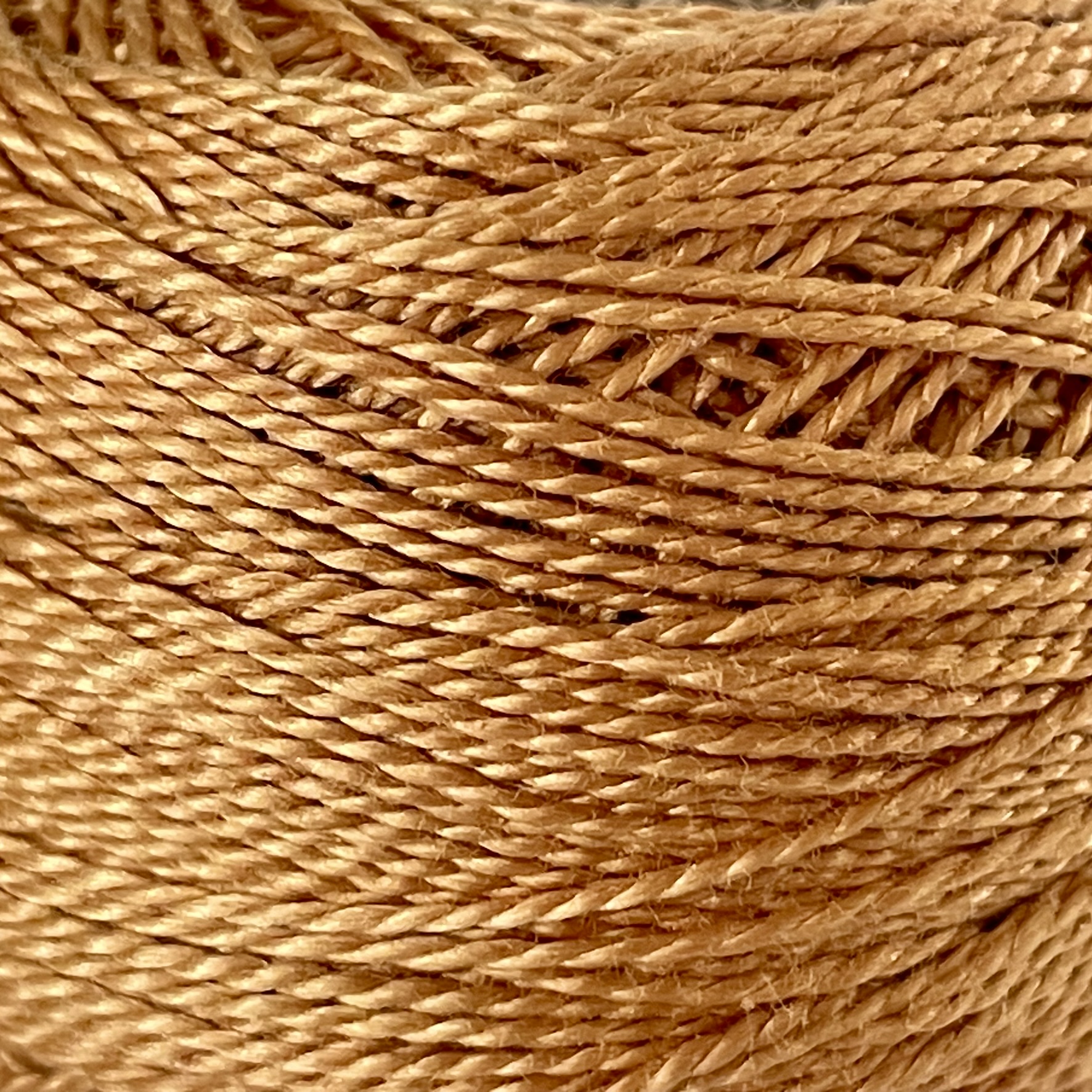 A DMC Cotton Perle 116 / 436 / 8 (Light Brown) ball of 100%, mercerised cotton thread that has been manufactured using a twisting process so it iis non-divisible.