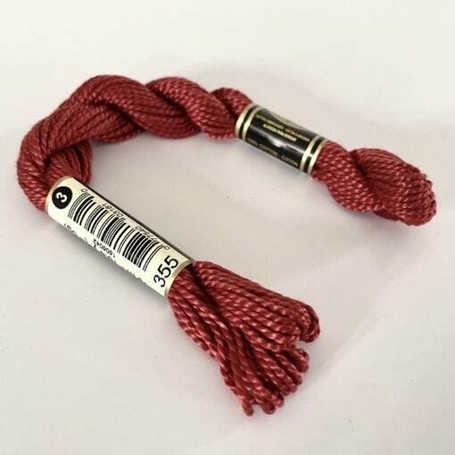 A DMC Cotton Perle in shade 355 (size 3) skein of 100%, mercerised cotton embroidery thread manufactured using a twisting process so it is non-divisible.